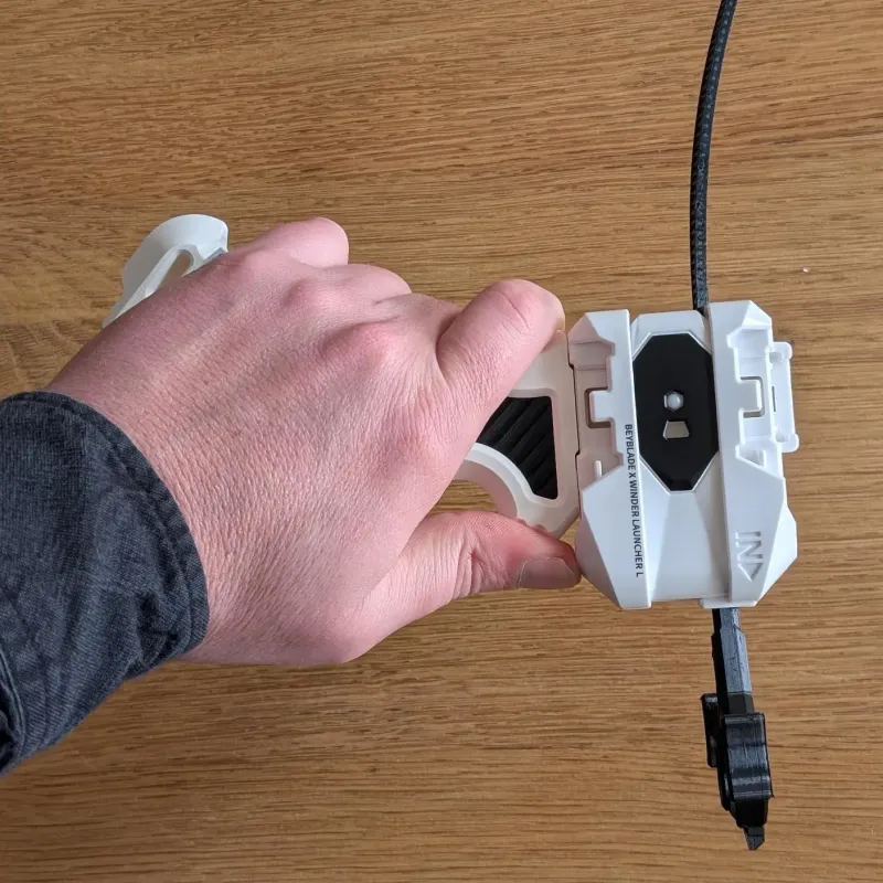 Top view of 3D printed Bakuten-style Beyblade X grip in hand with a beyblade loaded