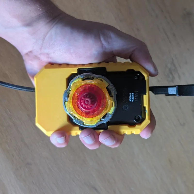 Player holding custom Beyblade X inline launcher grip designed for competitive launch control